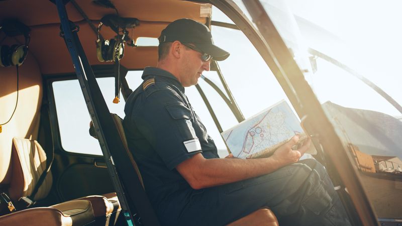 Helicopter pilot reading air map on while grounded