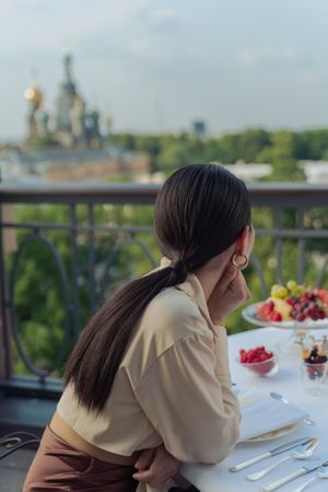 Back view of woman sitting at dinner table on terrace