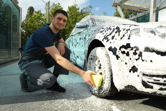 Man wipes the car with a sponge. Car wash. Clear car concept