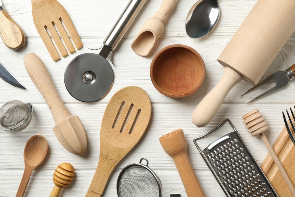 Different kitchen cutlery on wooden background