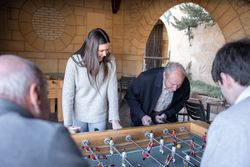 A granddaugther and his grandfather are playing table football game and having fun together