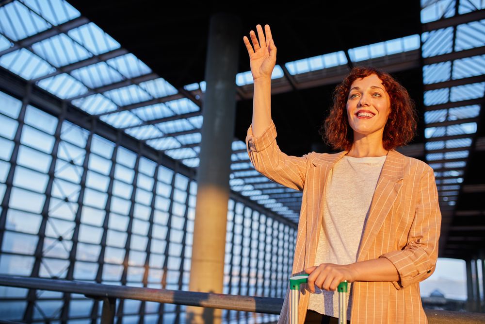 Young female traveler waving hand at station