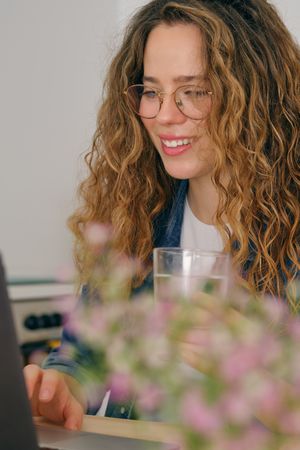 Smiling woman with curly hair using laptop