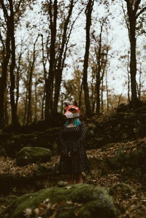 Woman in red fox mask walking in forest