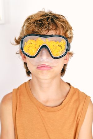 Boy in diving mask with petals on light background