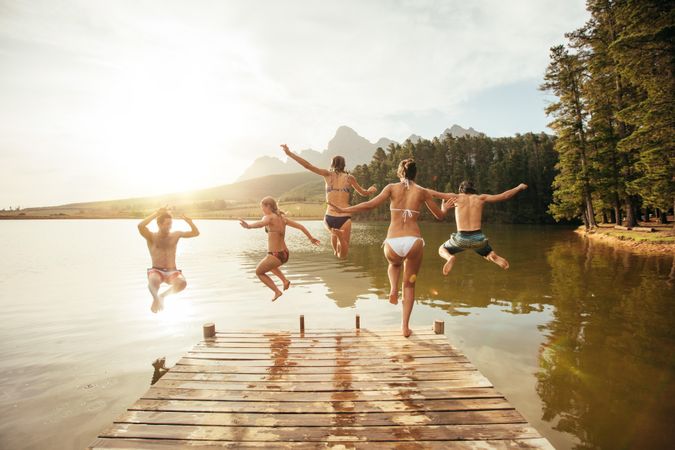 Portrait of young friends jumping into the water from a dock