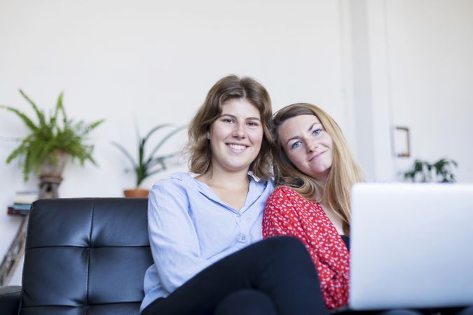 Smiling couple using computer while sitting on couch
