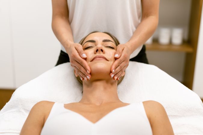 Symmetrical shot of woman having her face massaged by massage therapist