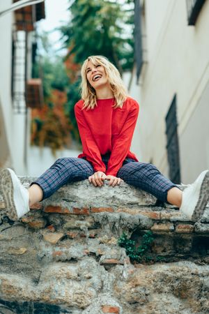 Laughing blond woman sitting on stone wall
