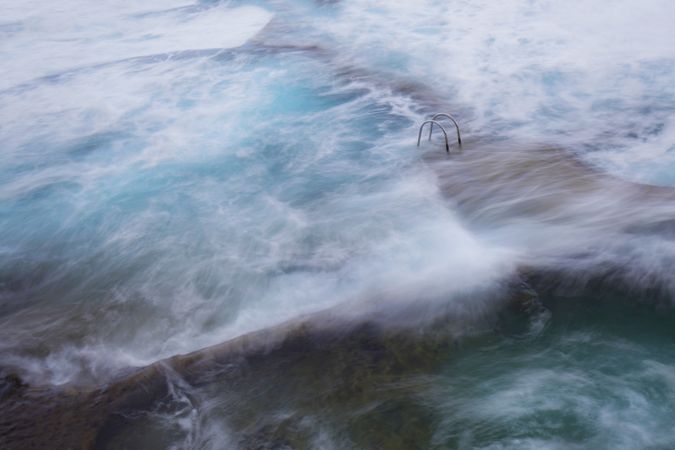 Stone shore with ladder between water