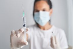 Woman in face mask holding syringe