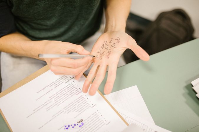 Person writing a math equation on their hand as part of cheating on exam