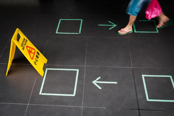 Person walking towards caution wet floor sign