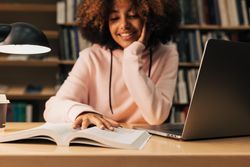 Teenage female student doing homework in library