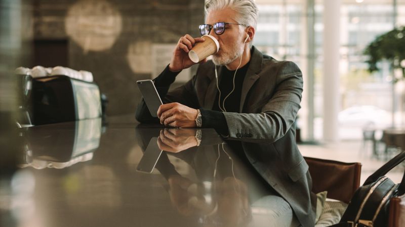 Businessman sitting at a cafe drinking coffee and using smart phone