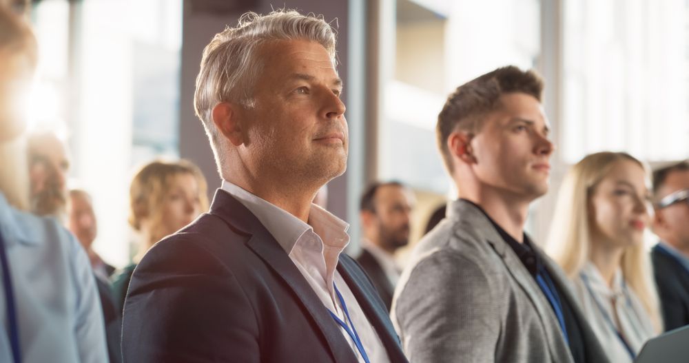 Close Up Of Caucasian Man Sitting in Crowded Audience at Business Conference And Using Laptop. Company Delegate Watching Entrepreneurship Presentation About Developing Markets, Financial Opportunities
