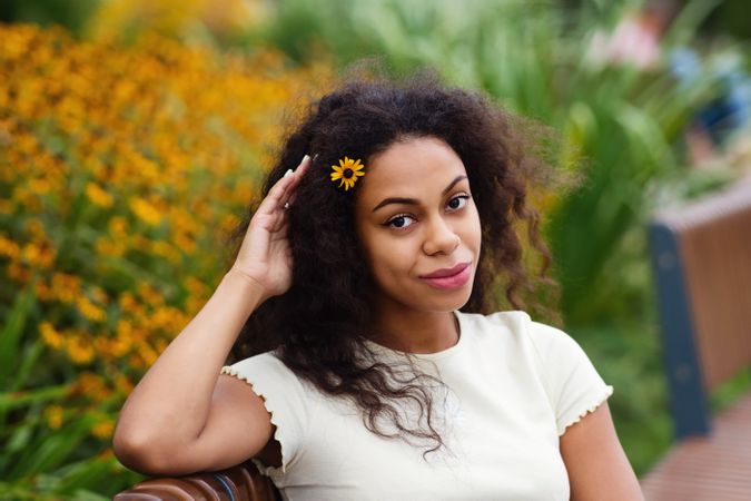 Black female sitting on bench with yellow flower in hair