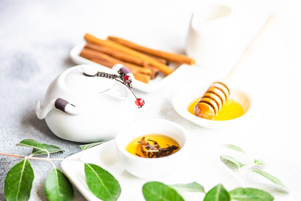 Cup of fragrant tea from pot served with honey