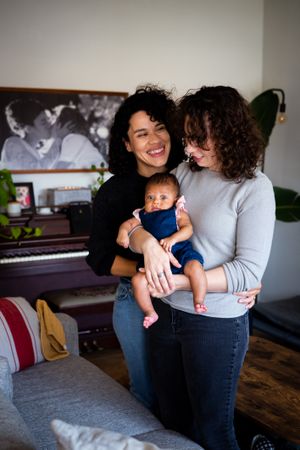 Loving couple with their baby daughter in the living room, vertical