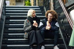 Couple eating rolls while sitting on the stairs