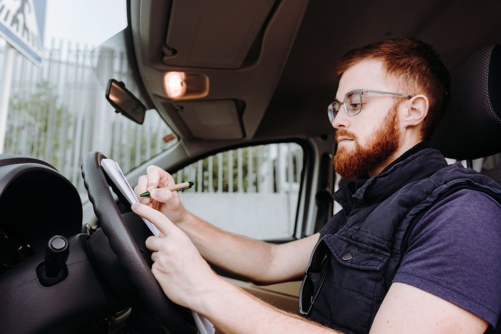 Courier filling papers while preparing for delivery of order to client in car