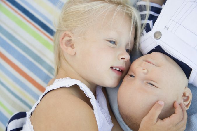 Little Sister Laying Next to Her Baby Brother on Blanket