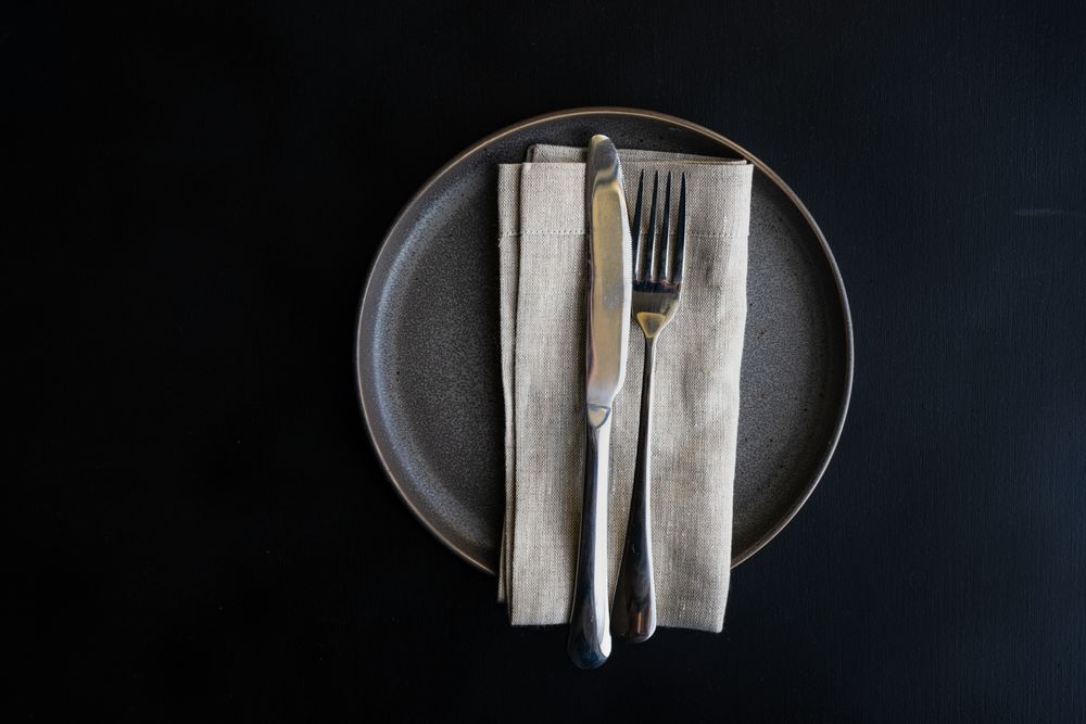 Top view of dark grey plate and napkin with space for text