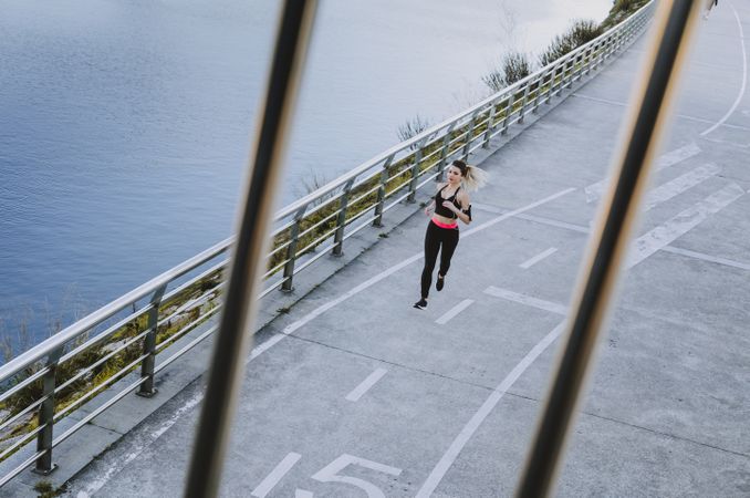 Young woman running on embankment near water