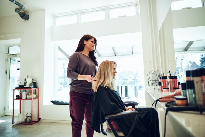 Hairdresser looking at clients hair in mirror reflection