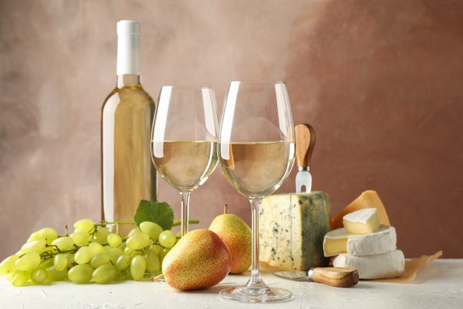 Grape, cheese, pears, glasses and bottle with wine, on plain background, copy space