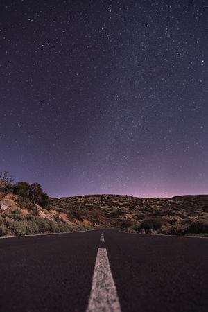 Empty road at night under bright stars