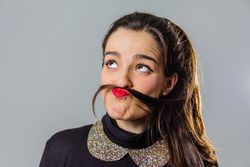 Woman with red lips using her hair like a moustache
