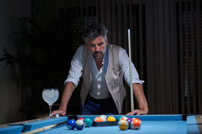 Thoughtful mature male contemplating balls while playing billiard