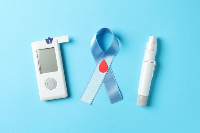 Blue awareness ribbon and diabetes accessories on blue background