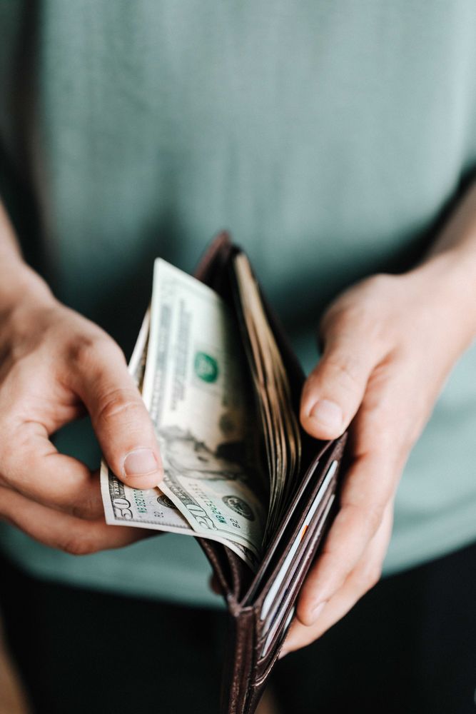 Cropped image of person counting the dollar bills in wallet