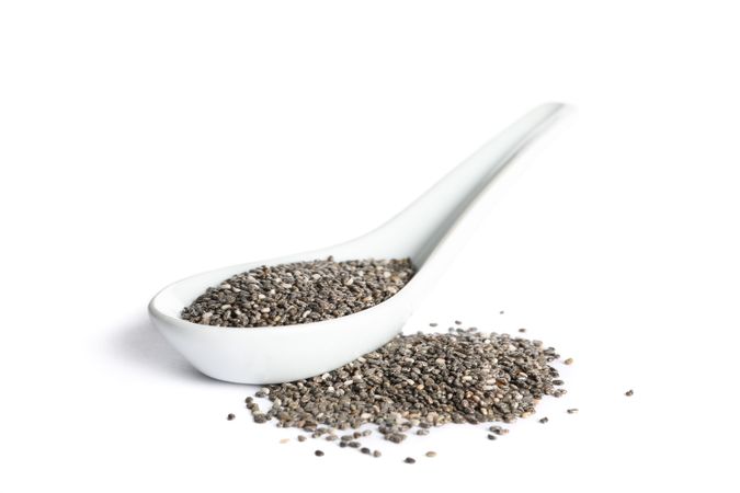 Chia seeds in porcelain spoon isolated on plain background