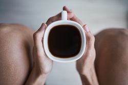Faceless woman drinking coffee in room