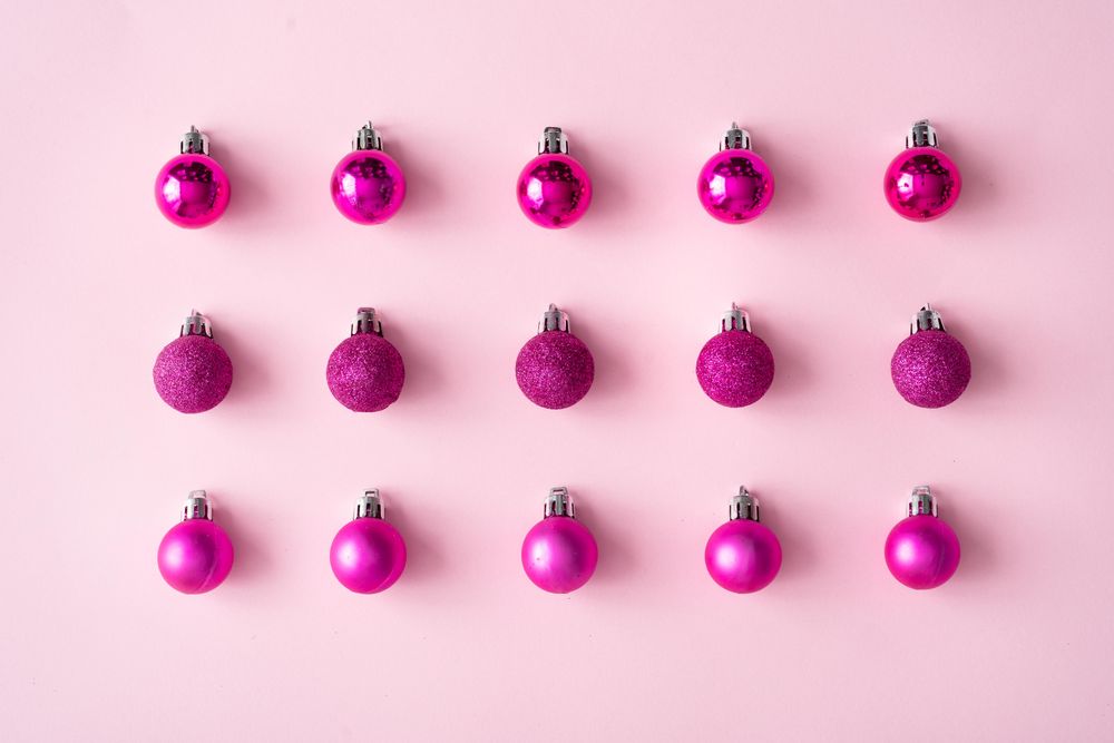Arrangement of pink festive baubles in rows on pink background