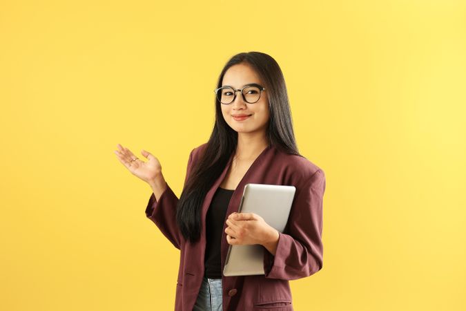 Asian Female Executive with Long Hair Smile Holding Tablet for Work Pointing on the Left Side.