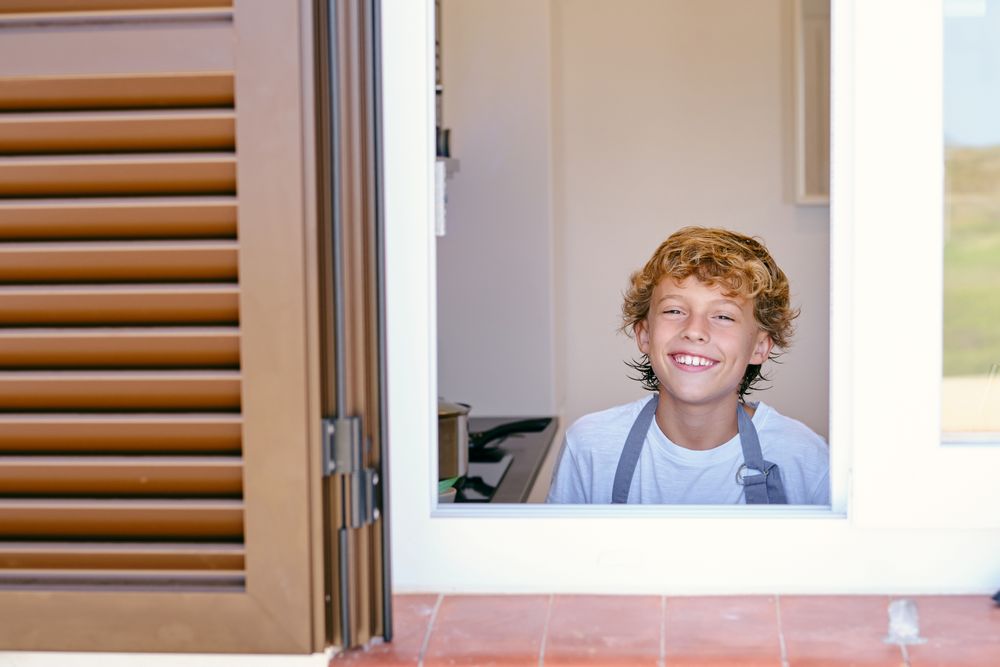 Smiling boy in kitchen against house window