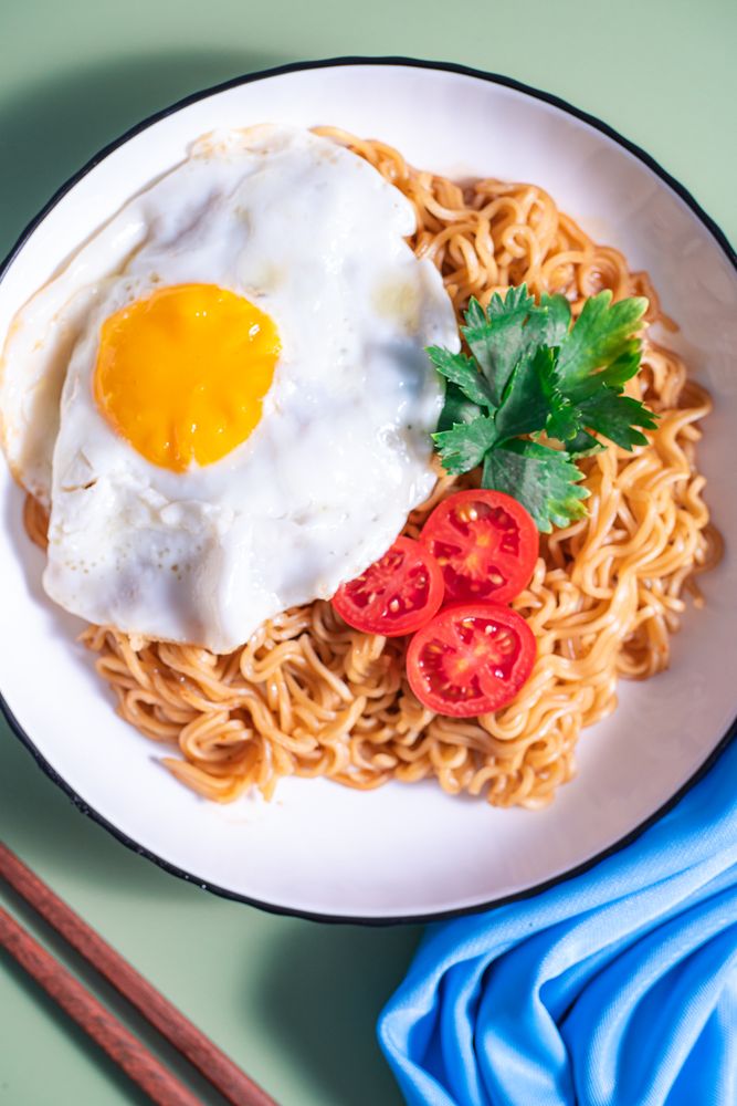 A plate of noodles with an egg and tomato on top