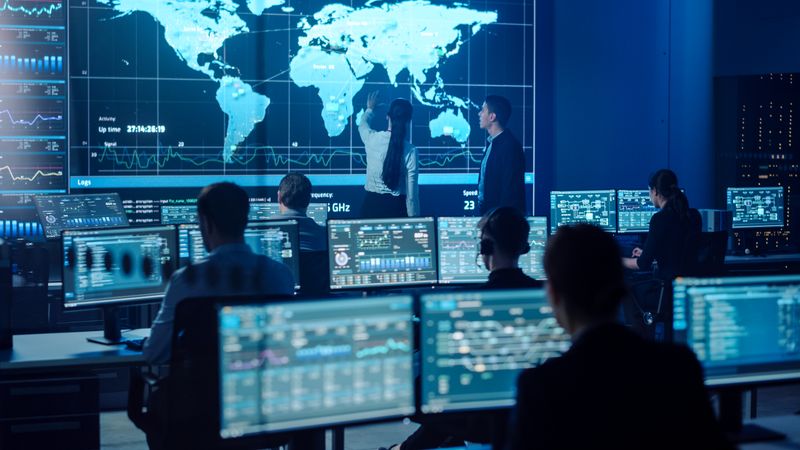 Diverse Team in a Cutting-edge Control Room Analyzes Global Data on Multiple Screens, Focusing on Cybersecurity and Network Efficiency for Seamless Digital Operations and Communication.