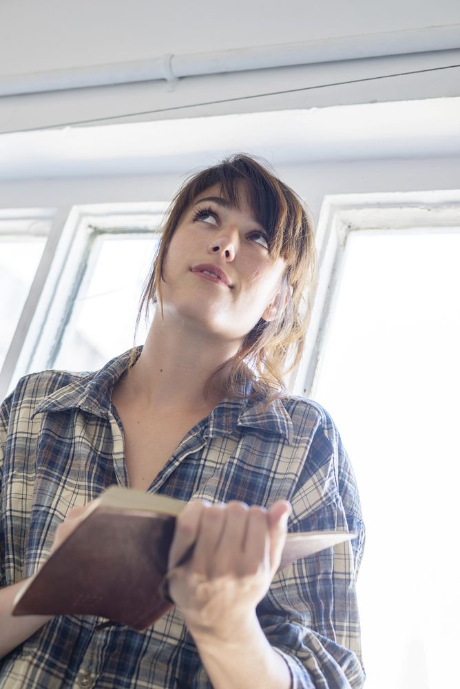 Looking up at woman reading book on stairs, vertical