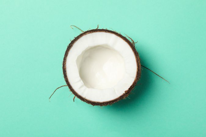 Half of coconut on mint background, top view