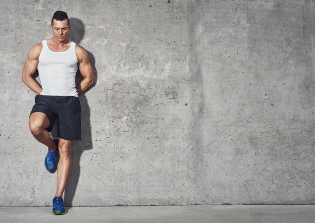 Muscular man leaning against wall