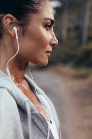 Close up of female runner with earphones standing outdoors
