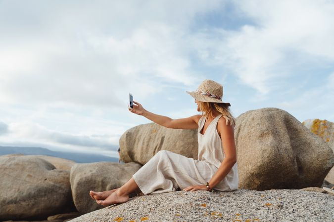 Contemporary woman with phone chilling on seashore
