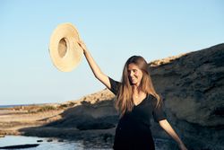 Cheerful woman holding hat in air