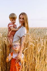 Young mother with little sons standing on wheat field in countryside