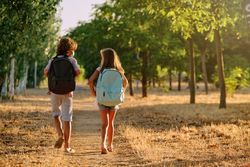 Boy and girl with backpacks walking on path